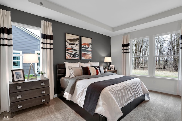 carpeted bedroom featuring a tray ceiling, visible vents, and baseboards