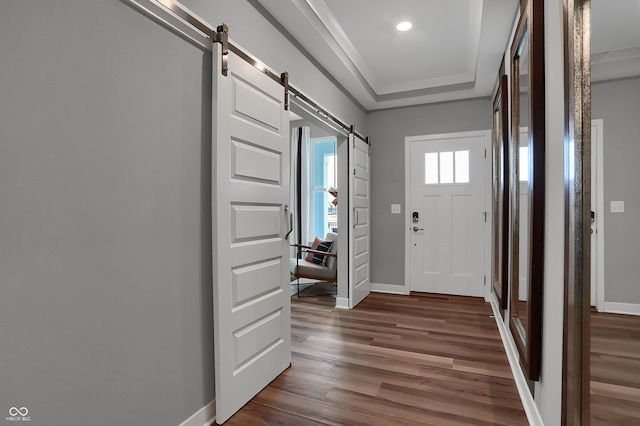 foyer featuring a barn door, baseboards, a raised ceiling, and dark wood-type flooring