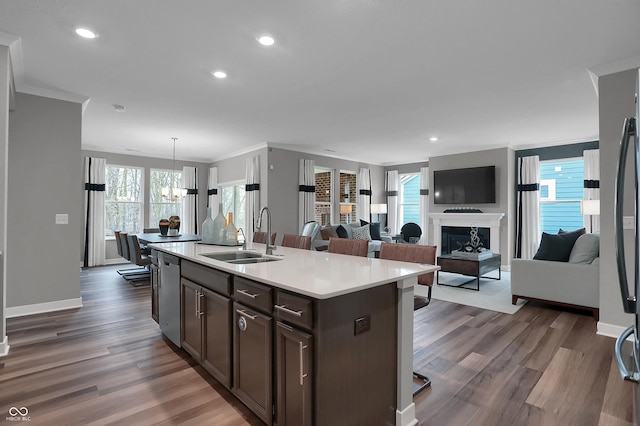 kitchen featuring dark brown cabinetry, a sink, light countertops, a fireplace, and stainless steel dishwasher