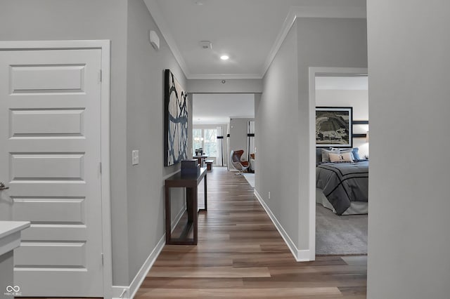 corridor with ornamental molding, baseboards, and wood finished floors