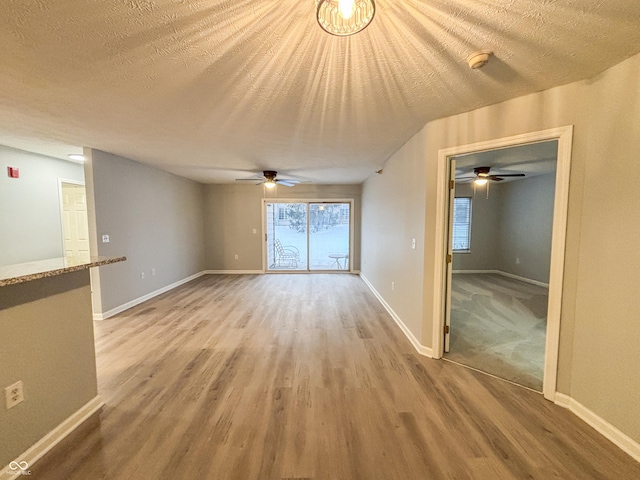 unfurnished living room featuring a textured ceiling, ceiling fan, and light wood-type flooring