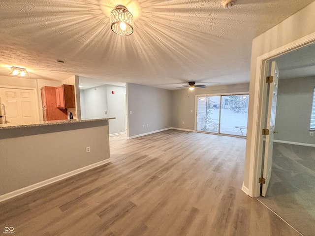 unfurnished living room with hardwood / wood-style floors, a textured ceiling, and ceiling fan