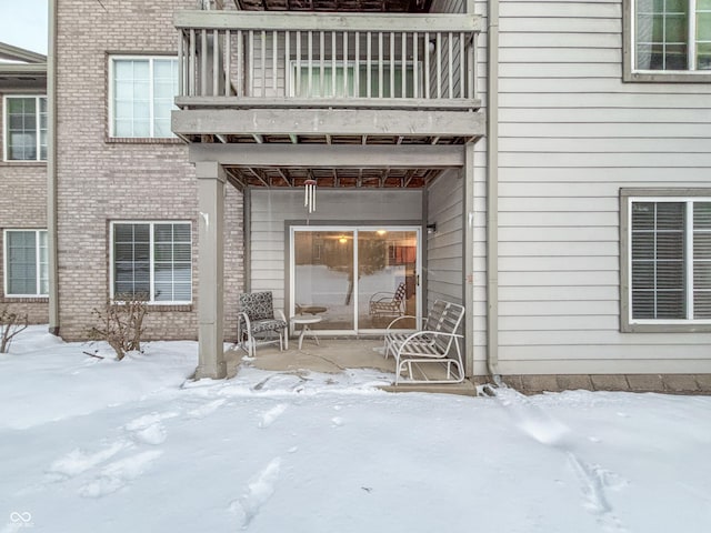 snow covered property entrance with a balcony