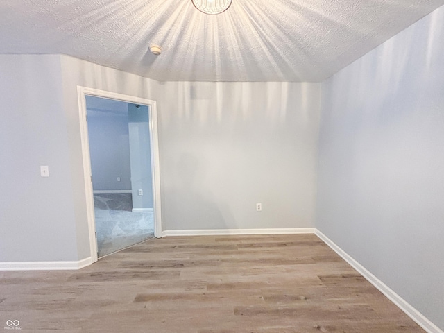 spare room with a textured ceiling and light wood-type flooring