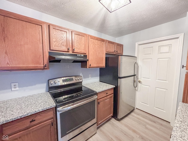 kitchen featuring stainless steel appliances, a textured ceiling, light hardwood / wood-style floors, and light stone counters