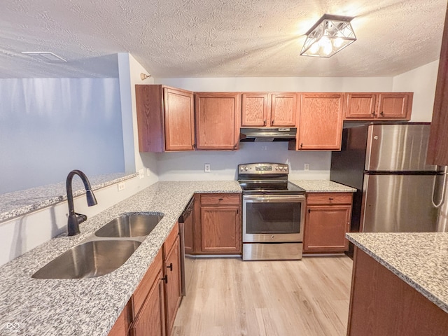 kitchen featuring a textured ceiling, appliances with stainless steel finishes, light hardwood / wood-style floors, and sink