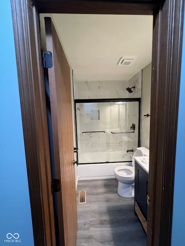 full bathroom with vanity, toilet, enclosed tub / shower combo, a textured ceiling, and wood-type flooring