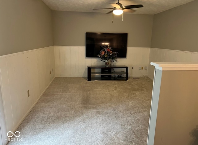 interior space with light carpet, ceiling fan, and a textured ceiling