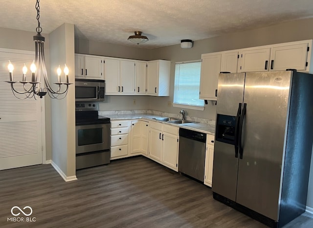 kitchen with appliances with stainless steel finishes, a textured ceiling, sink, decorative light fixtures, and white cabinetry