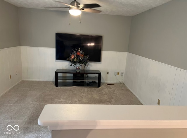 carpeted living room with ceiling fan and a textured ceiling