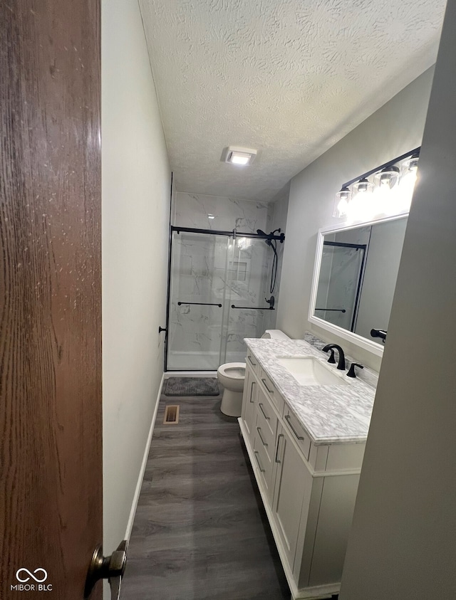 bathroom with vanity, toilet, a textured ceiling, walk in shower, and wood-type flooring