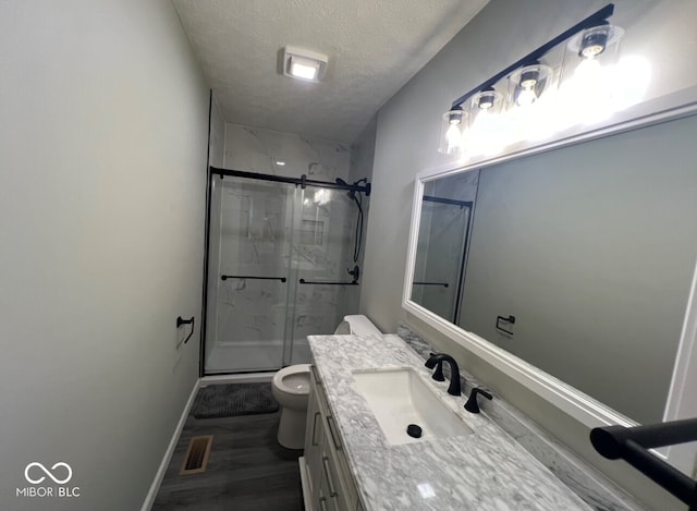 bathroom with vanity, hardwood / wood-style flooring, toilet, a textured ceiling, and walk in shower