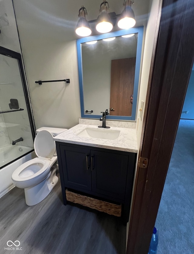 full bathroom with vanity, hardwood / wood-style flooring, toilet, and enclosed tub / shower combo