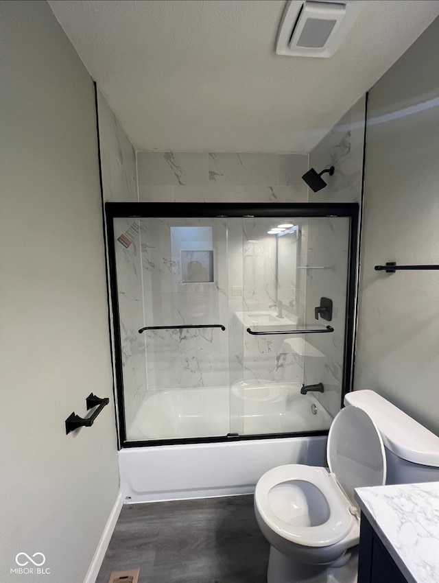 full bathroom featuring toilet, vanity, bath / shower combo with glass door, and hardwood / wood-style flooring