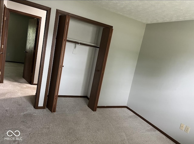 unfurnished bedroom with light carpet, a textured ceiling, and a closet