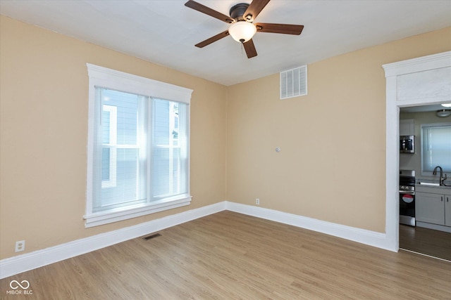 unfurnished room featuring sink, light hardwood / wood-style floors, and ceiling fan