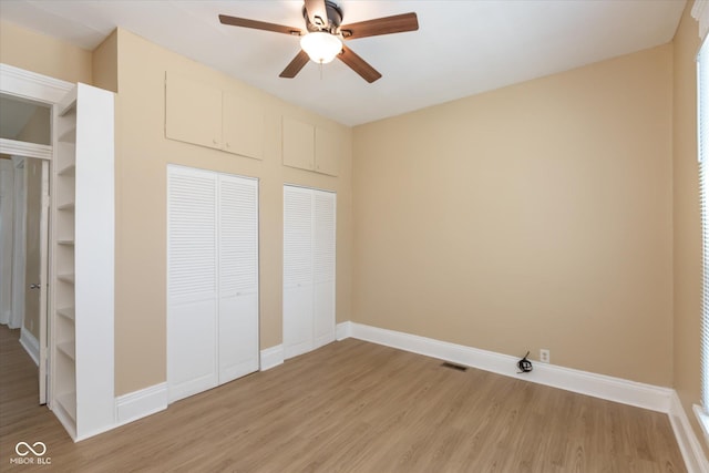 unfurnished bedroom with multiple closets, ceiling fan, and light wood-type flooring