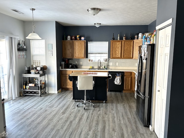 kitchen with black appliances, a center island, pendant lighting, a breakfast bar, and sink