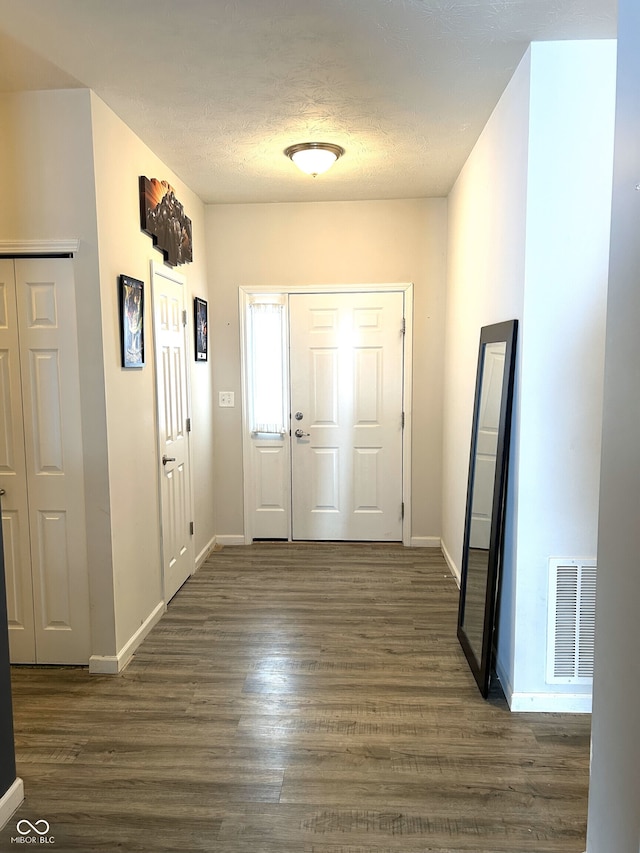 foyer entrance featuring a textured ceiling and dark hardwood / wood-style floors