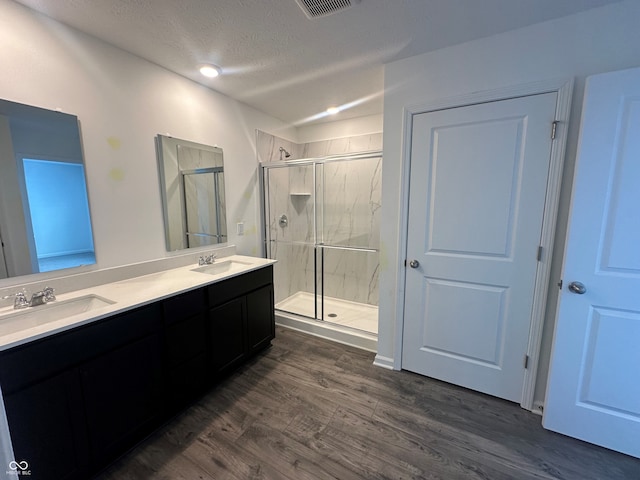 bathroom with a shower with door, lofted ceiling, wood-type flooring, a textured ceiling, and vanity