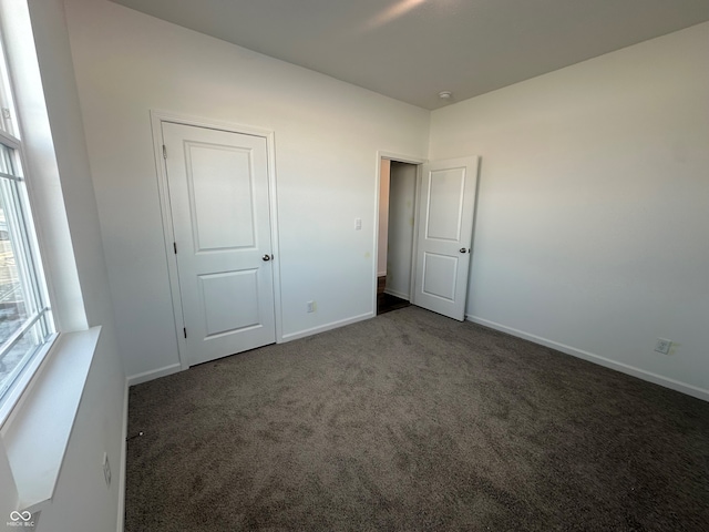 unfurnished bedroom with dark colored carpet