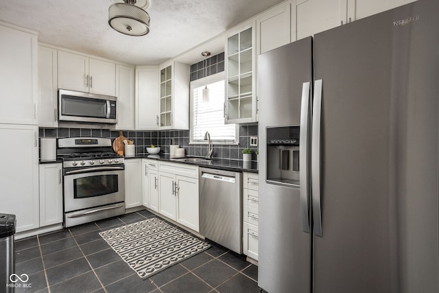 kitchen featuring white cabinets, stainless steel appliances, a textured ceiling, dark tile patterned floors, and sink