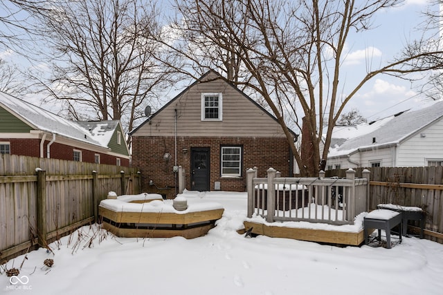 snow covered rear of property with a wooden deck