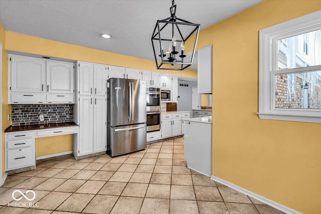 kitchen with white cabinets, decorative backsplash, hanging light fixtures, and appliances with stainless steel finishes