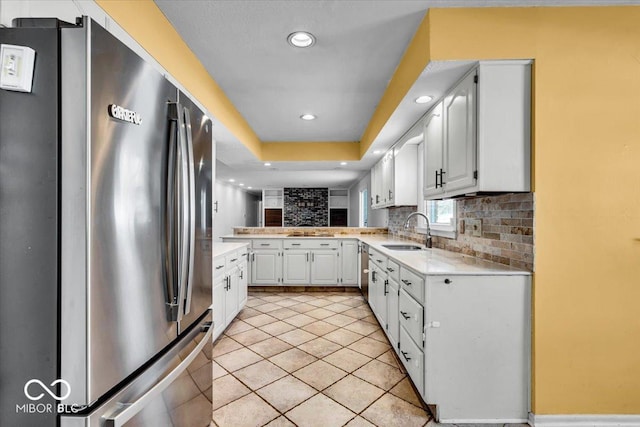 kitchen featuring stainless steel appliances, light tile patterned floors, decorative backsplash, white cabinets, and sink