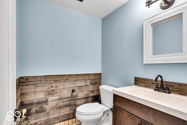 bathroom featuring toilet, a textured ceiling, and vanity