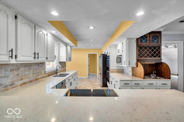 kitchen with appliances with stainless steel finishes, white cabinetry, backsplash, and sink