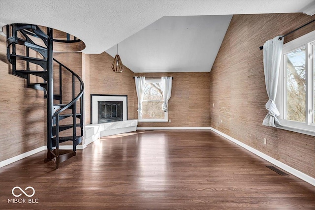 unfurnished living room featuring vaulted ceiling, a textured ceiling, and hardwood / wood-style flooring