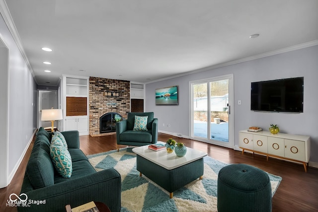 living room with built in shelves, a brick fireplace, crown molding, and dark hardwood / wood-style floors