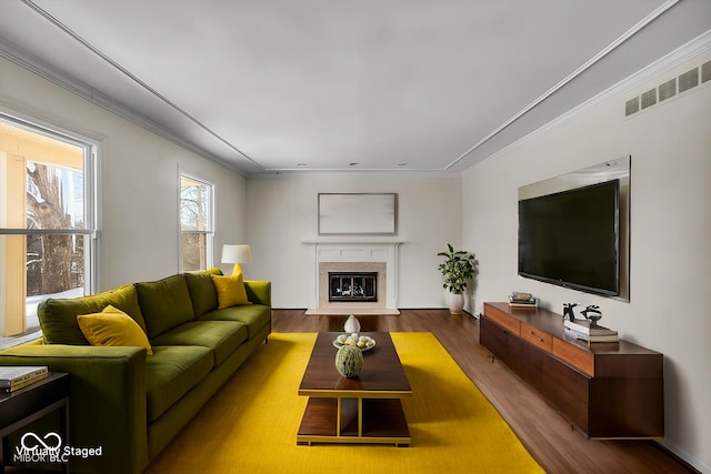 living room with a high end fireplace, ornamental molding, and hardwood / wood-style flooring