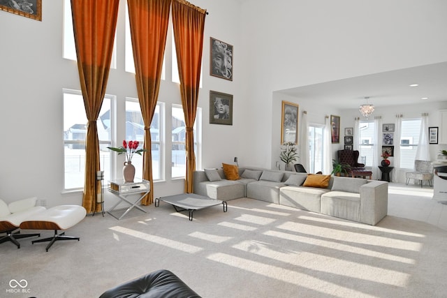 living room with light colored carpet, a towering ceiling, and a chandelier