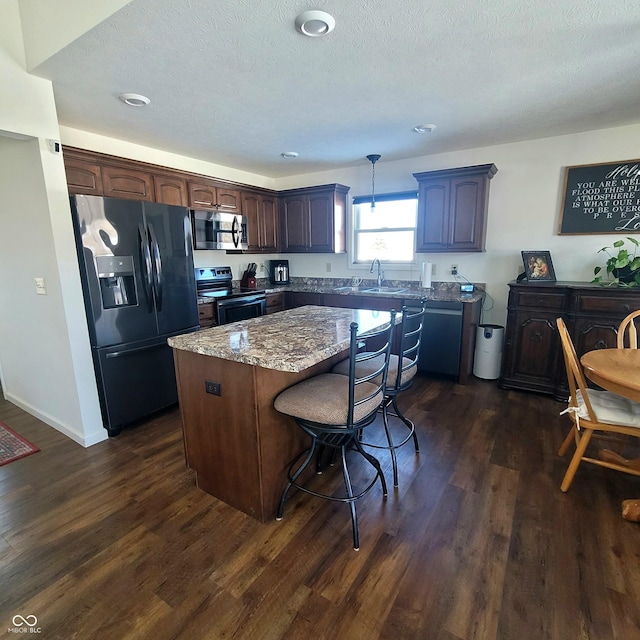 kitchen featuring sink, dark hardwood / wood-style flooring, a kitchen island, and appliances with stainless steel finishes