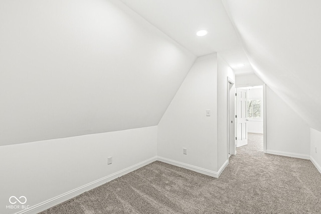 additional living space featuring carpet flooring, baseboards, and vaulted ceiling