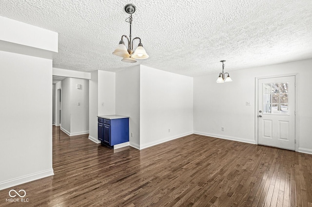 interior space featuring baseboards, a textured ceiling, a chandelier, and dark wood-style flooring