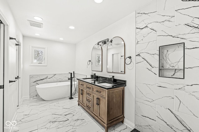 full bath featuring double vanity, recessed lighting, a sink, a freestanding bath, and marble finish floor