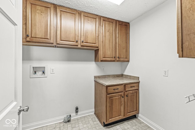 washroom featuring cabinet space, a textured ceiling, baseboards, and washer hookup