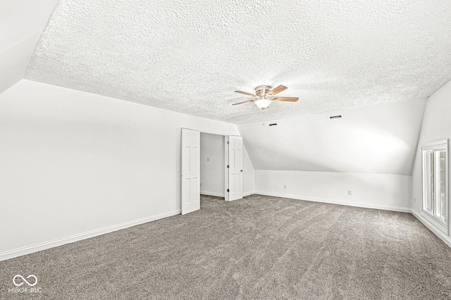 bonus room featuring ceiling fan, vaulted ceiling, carpet, and a textured ceiling