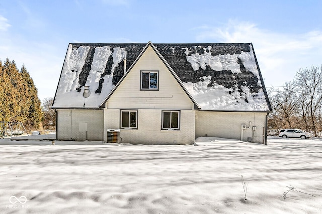 snow covered rear of property with brick siding