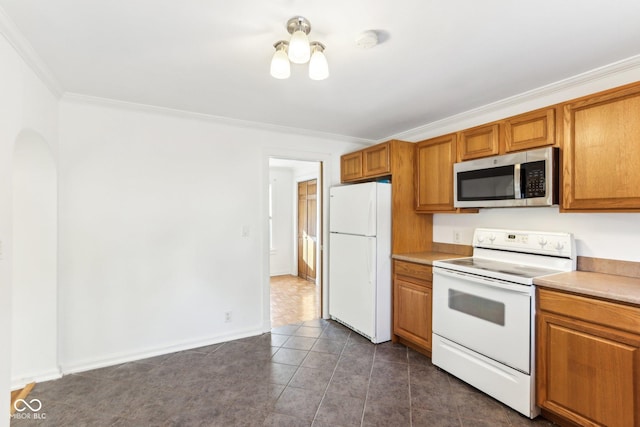 kitchen featuring white appliances, dark tile patterned floors, and ornamental molding