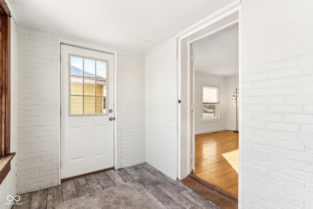 entryway with a wealth of natural light, brick wall, and hardwood / wood-style floors