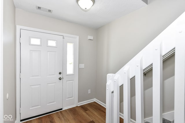 foyer entrance with a textured ceiling and dark hardwood / wood-style floors