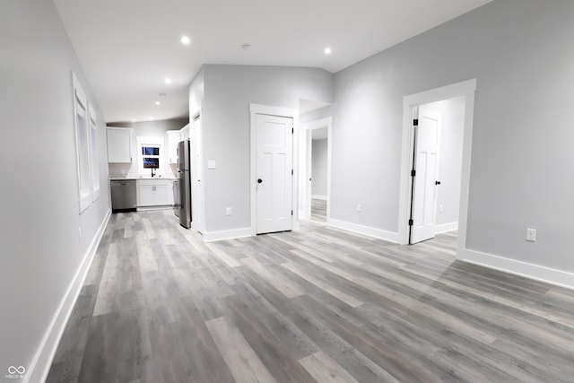 unfurnished living room featuring vaulted ceiling and light hardwood / wood-style floors