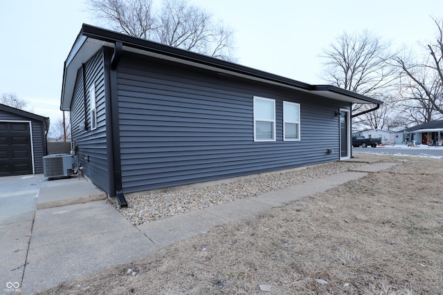 view of side of home with a garage and central AC