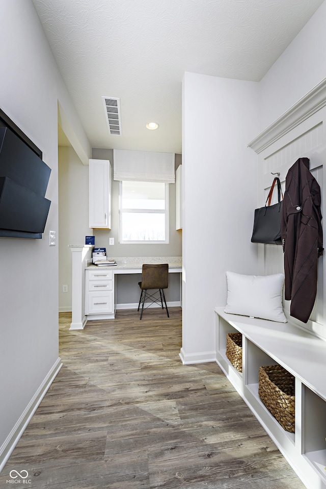 mudroom with built in desk and wood-type flooring