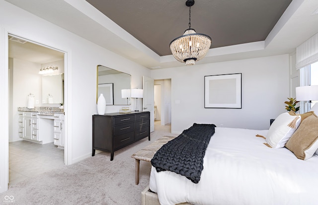 carpeted bedroom with an inviting chandelier, a raised ceiling, and ensuite bath