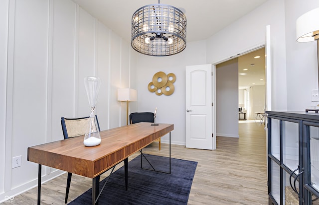 home office with light hardwood / wood-style flooring and an inviting chandelier